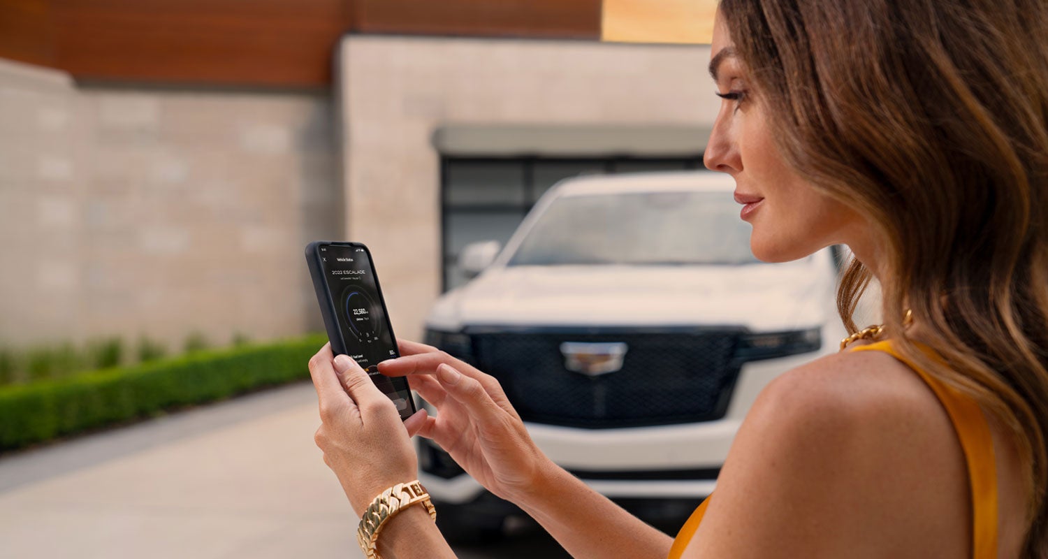 lady checking her mobile with a Cadillac vehicle background | Vaughn Automotive - Cadillac of Ottumwa in OTTUMWA IA